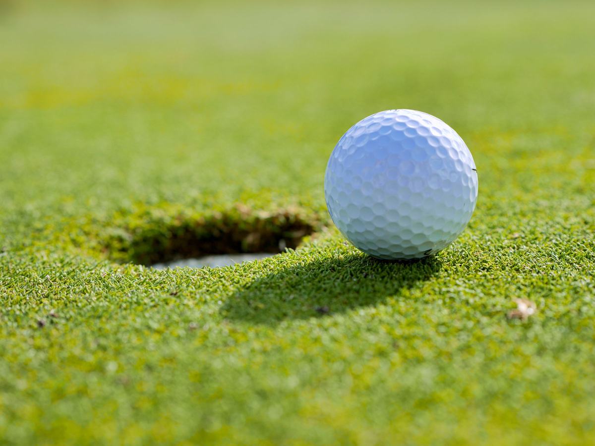 A golf ball stopped on the lip of the cup